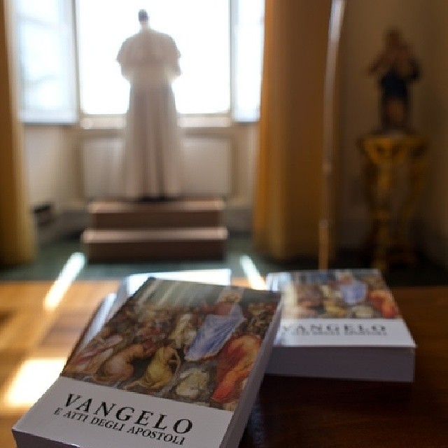 Papa Francisco rezando o Angelus deste domingo e em primeiro plano os livros dos Evangelhos distribuídos ao povo.