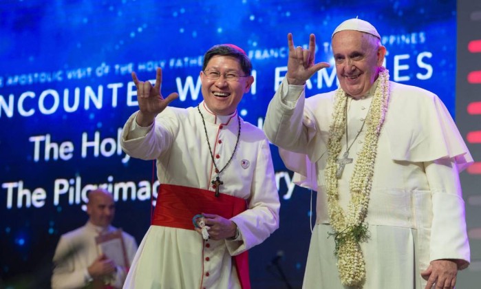 O Papa Francisco e o acerbispo de Manila, Luis Antonio Tagle, cumprimentam público com gesto popular - - / AFP 