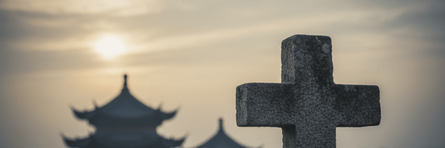 Uma cruz de pedra em primeiro plano, com telhados tradicionais chineses ao fundo, simbolizando a presença cristã discreta na China